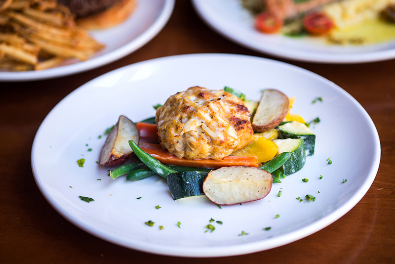 Crab cake with vegetables on a white plate